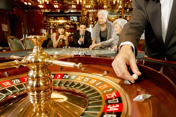 Croupier spinning a roulette wheel with players at a live casino table